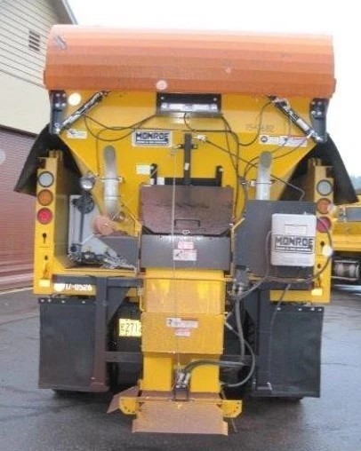 An image of a yellow PennDOT plow truck with an orange barrier mounted to the top of it, which protects the truck from buildup and keeps it clean